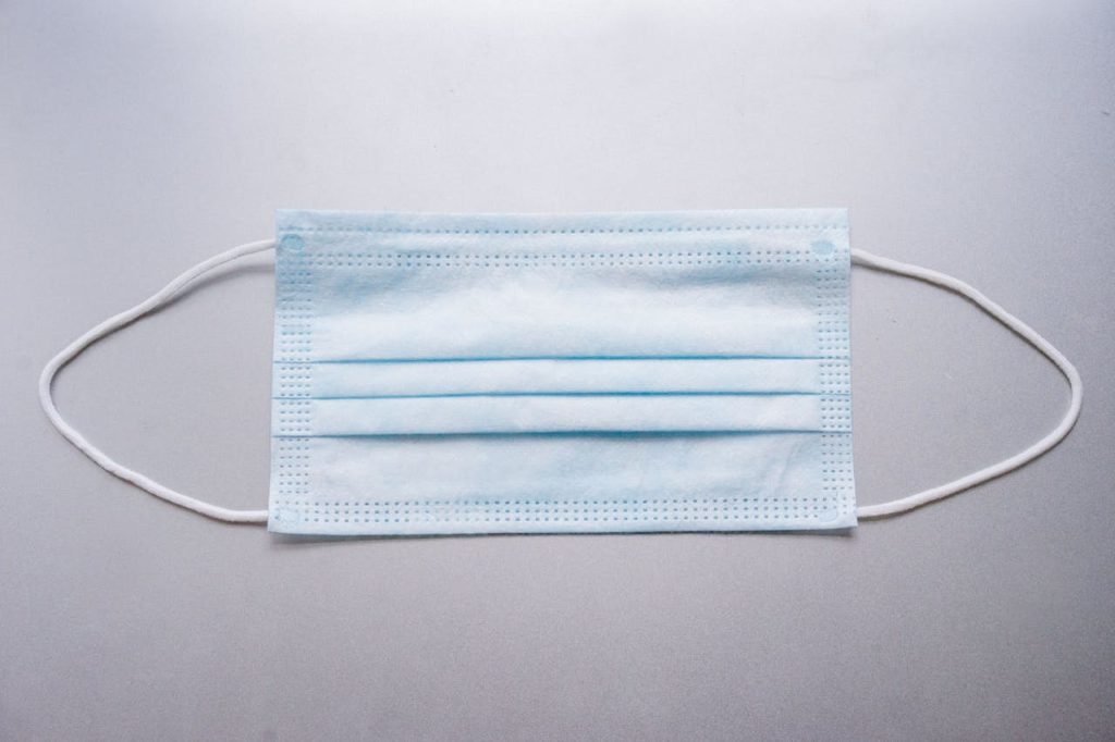 Close-up image of a blue surgical mask on a flat surface.